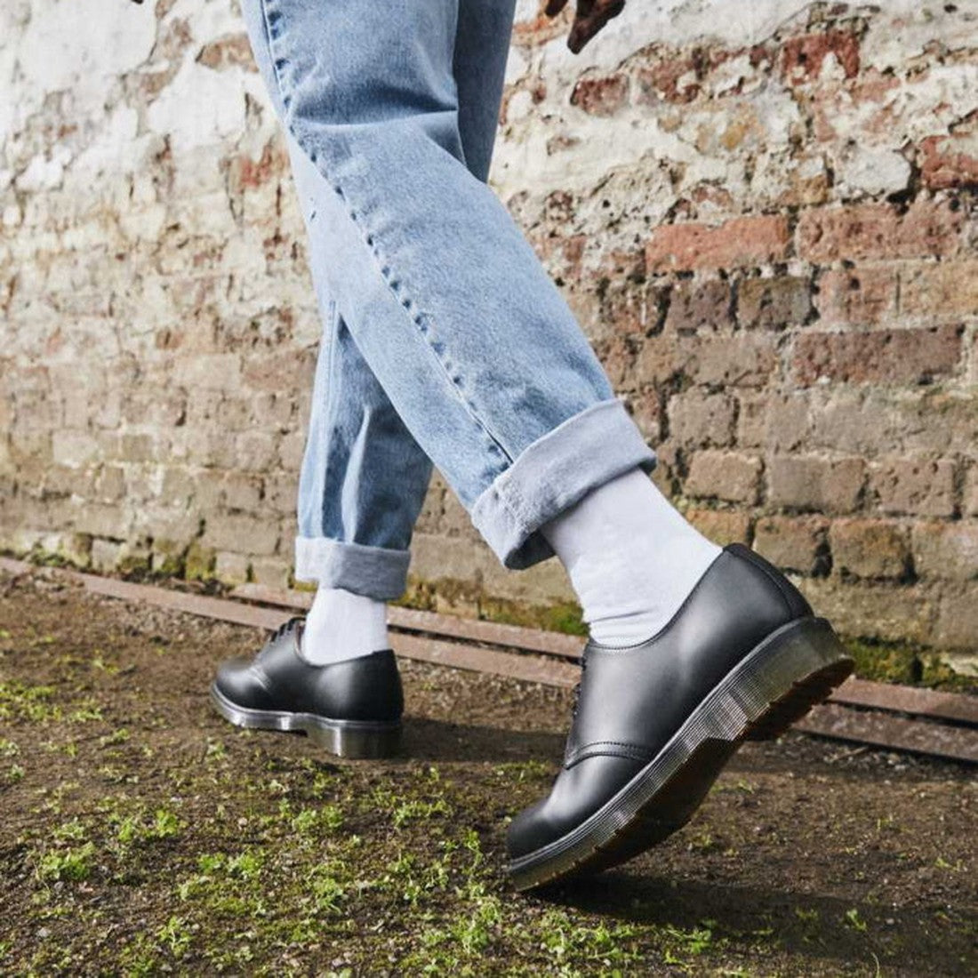 A child sports Dr Martens Doc Double Doc Sock Unisex White with sturdy black lace-up shoes, perfect for outdoor play and blister-free fun. ksnz, 190665563085, 190665563078