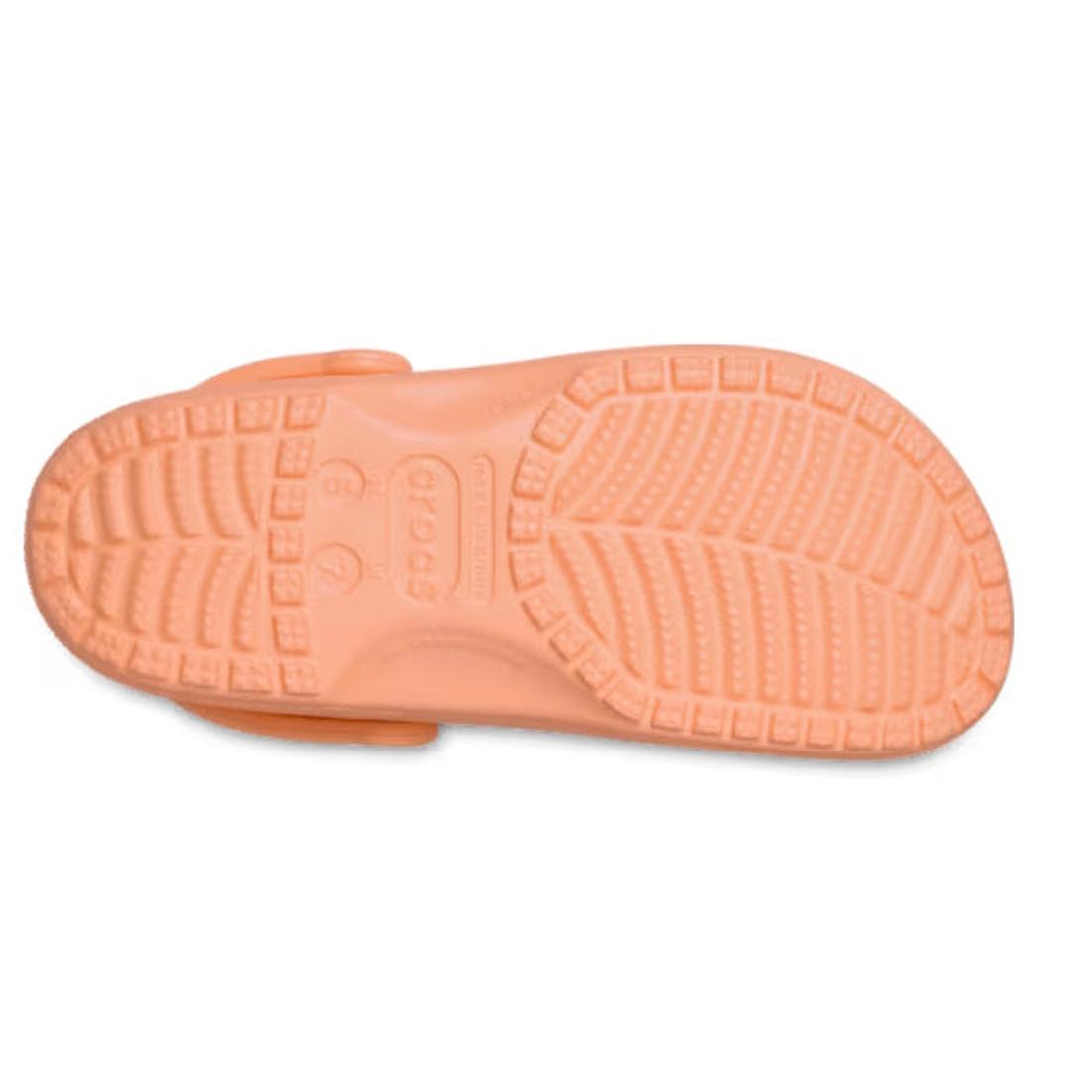 The image shows the sole of a Crocs - Classic Clog Adults Sunstone Soft Orange, viewed from below, featuring a textured tread for grip and the Crocs brand name embossed at the center., 47587, 198445262562, 198445262579, 198445262586, 47591, 47592, 47593, 