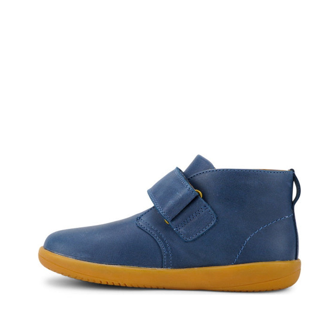 The Bobux Kid+ Desert Boot Midnight Blue 830312 is a children's unisex blue leather boot with a single Velcro strap, wide opening, and flat light brown rubber sole, displayed in profile on a white background., 9420068517035, 9420068517042, 9420068517059, 