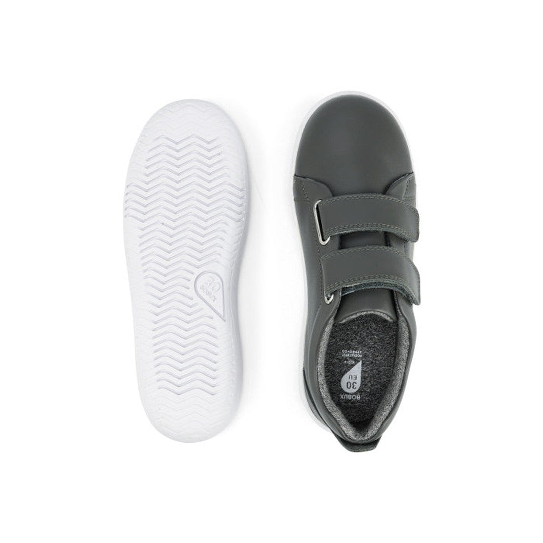 The Bobux Kids + Plus Grass Court Smoke Grey Velcro Trainers 832446 are dark gray kids’ shoes with white rubber soles, two velcro straps for easy fastening, and a textured sole for grip, shown from the top and bottom., 9420068518025, 9420068518032, 942006