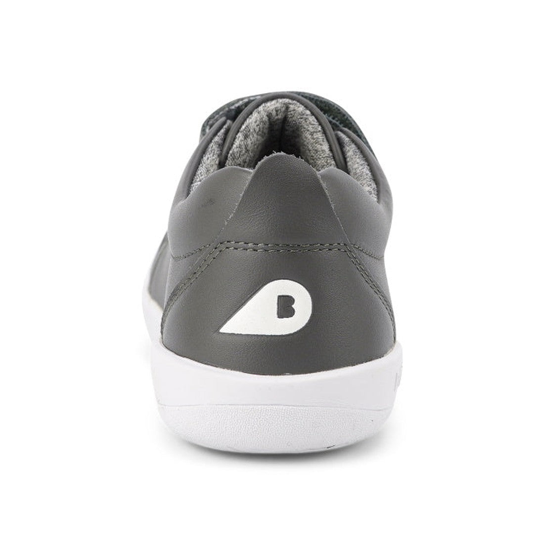 A close-up rear view shows the Bobux Kids + Plus Grass Court Smoke Grey Velcro Trainers 832446, featuring gray leather, a white sole, and a white B logo on the heel—perfect street shoes for kids—set against a plain white background., 9420068518025, 942006