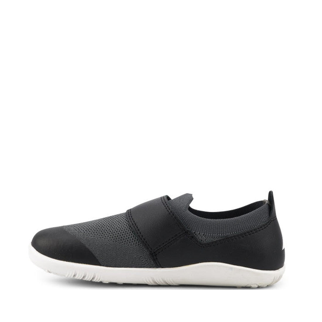 The Bobux Kid+ Lo Dimension III Black 838604 CLEARANCE is a black and gray slip-on sneaker with mesh upper, black toe cap, elastic top strap, and a lightweight flexible white sole, shown in side view on a plain white background., 9420068517202, 9420068517