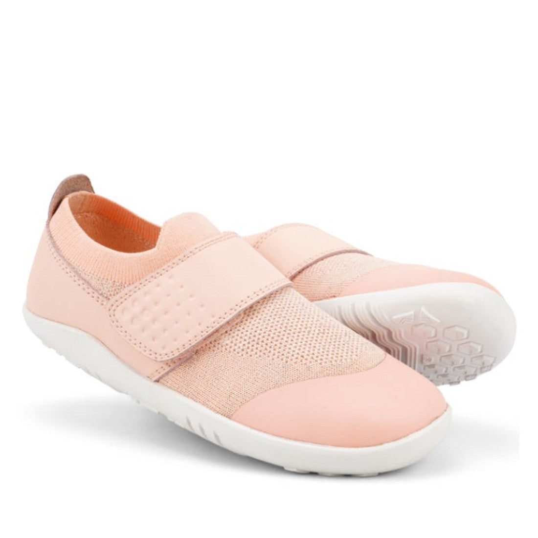 A pair of Bobux Kid+ Lo Dimension III Blossom Pink 838601 slip-on shoes with white soles, textured mesh upper, and a hook-and-loop strap. One kids flexible shoe stands upright; the other is angled to display the sole.