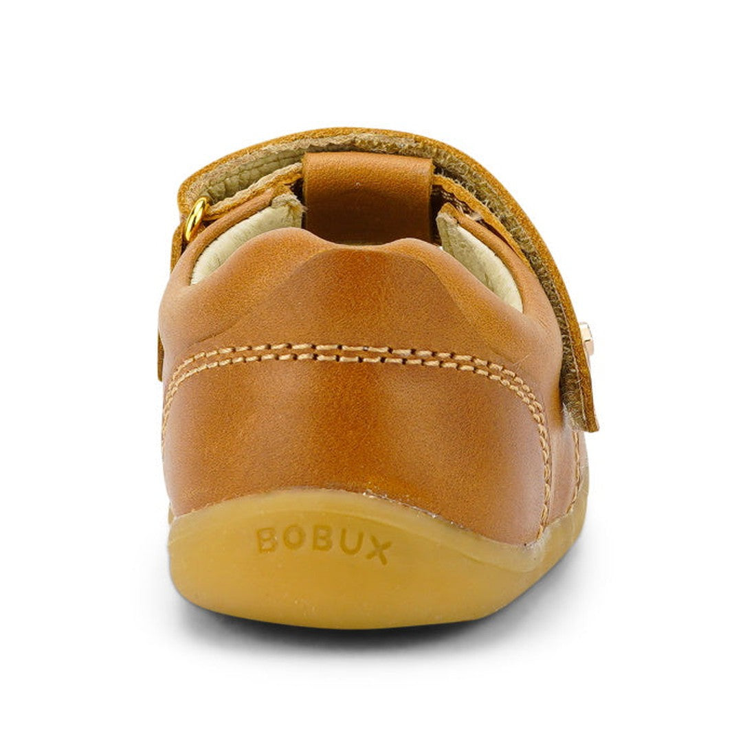 A rear view of the Bobux Step Up T-Bar Louise Tan Caramel 728318 shows its small brown leather design, soft rubber sole with BOBUX embossed on the heel, white stitching, and an adjustable velcro strap., 9420062092132, 9420062092149, 9420062092156, 9420062