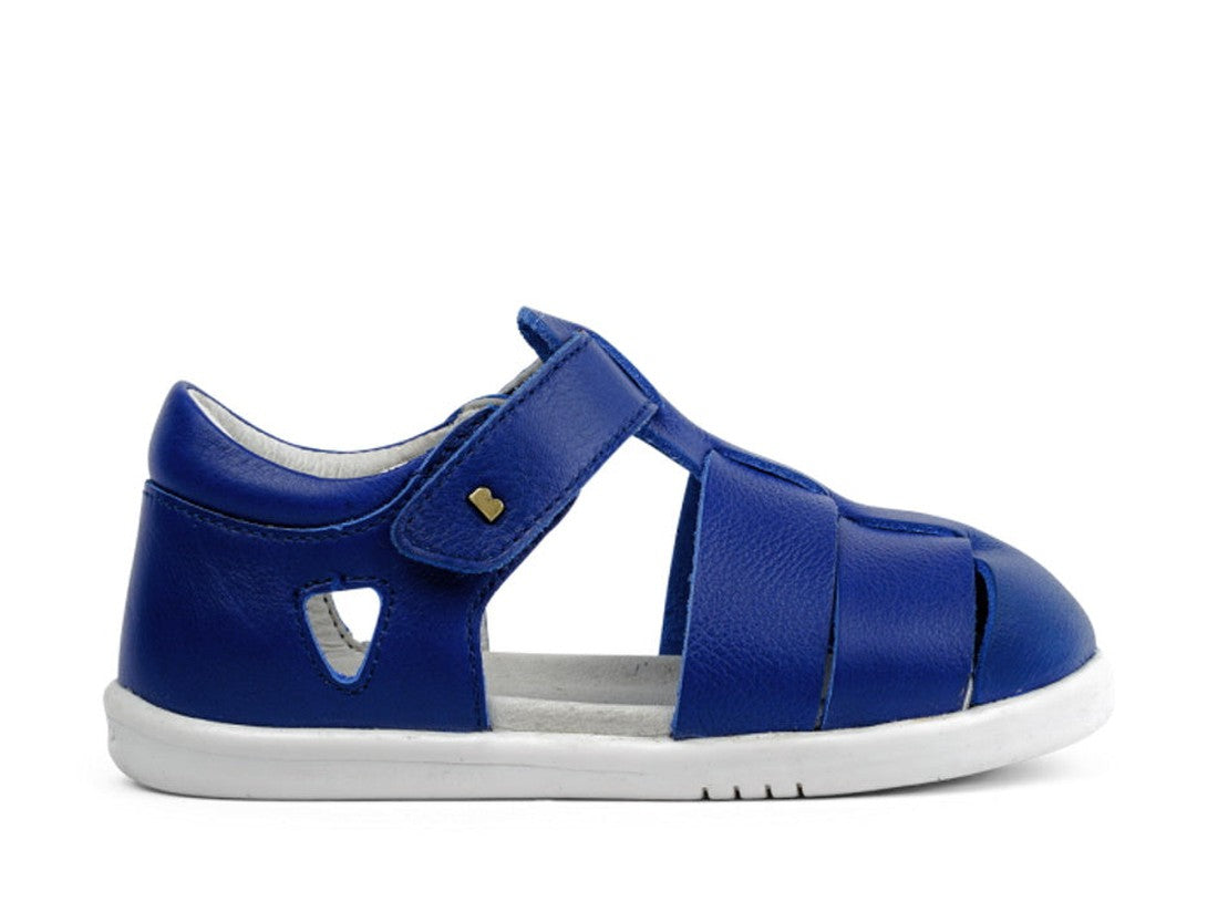 The Bobux Iwalk IW Quick Dry Tidal Sandal 634408 Blueberry is a unisex kids' blue leather closed-toe sandal with open sides, a white rubber sole, velcro strap, quick dry leather, and a heart-shaped accent near the strap., 9420062023624, 9420062023631, 942