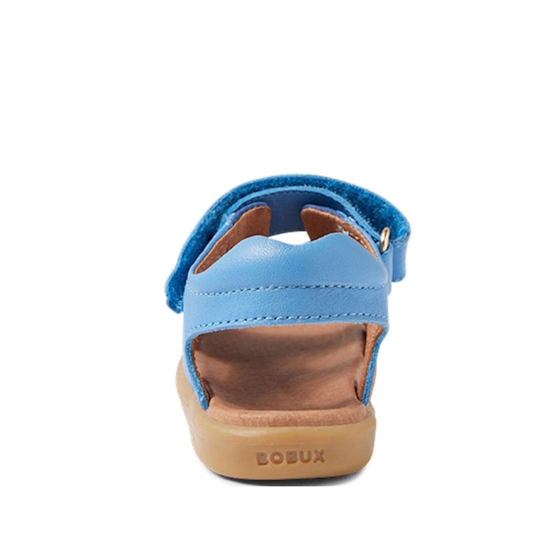 The Bobux IW Iwalk Strand Sandal in Azure Blue features a tan sole, open heel and toe, "BOBUX" on the back, and adjustable ankle straps for a secure fit—shown here from the rear view., 9420068556997, 9420068557000, 9420068557017, 9420068557024, 9420068557