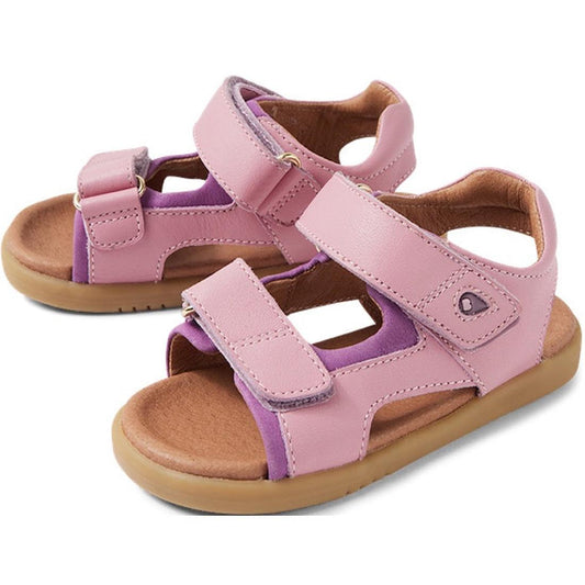 The Bobux IW Iwalk Strand Sandal Lilas Pink Open Toe for toddlers features adjustable Velcro straps, light brown soles, and purple accents on the inner lining.