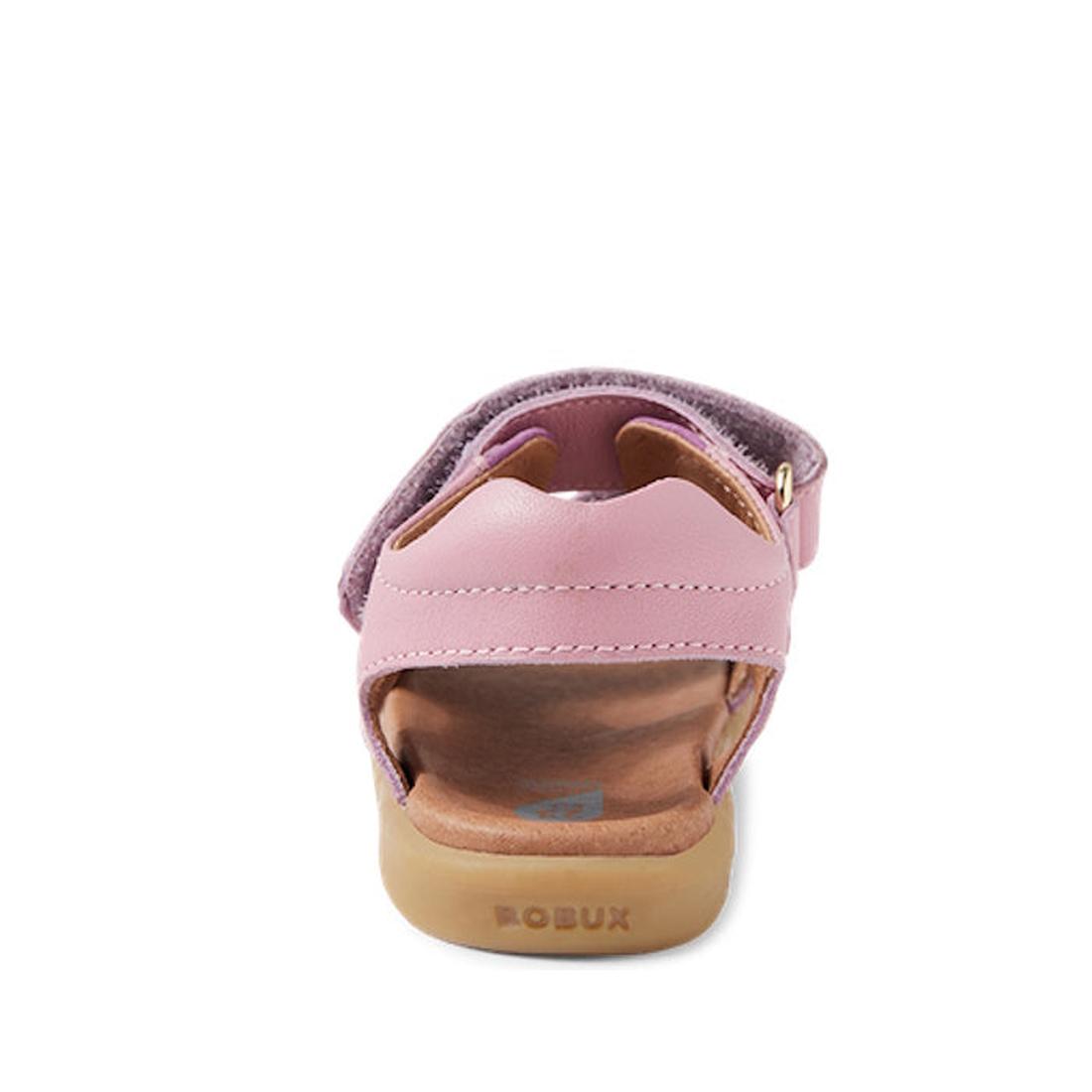 A rear view of the Bobux IW Iwalk Strand Sandal in Lilas Pink shows a kids' sandal with a tan sole, closed heel, open toe, and adjustable Velcro strap. The BOBUX brand name is embossed on the sole., 9420068556942, 9420068556959, 9420068556966, 94200685569