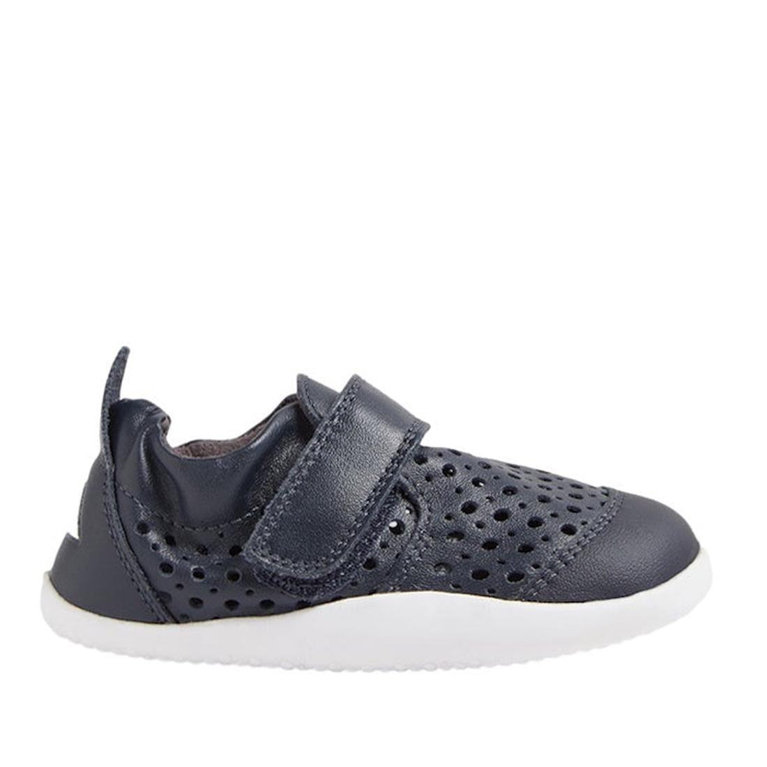 The Bobux Xplorer Go Punch Navy First Walker Sandal features perforated holes for breathability, a hook-and-loop strap, and a white rubber sole. Shown in side profile on a white background, these lightweight flexible baby shoes are perfect for little ones