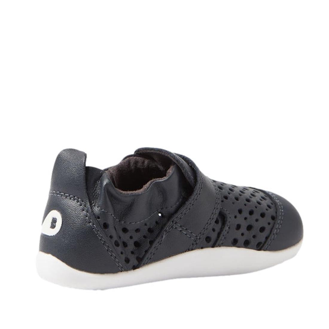 The Bobux Xplorer Go Punch Navy First Walker Sandal is a navy blue pre-walker with perforated holes, white sole, Velcro strap, and a white heel logo. This lightweight, flexible baby shoe is shown from the back side angle., 9420075786547, 9420075785717, 94