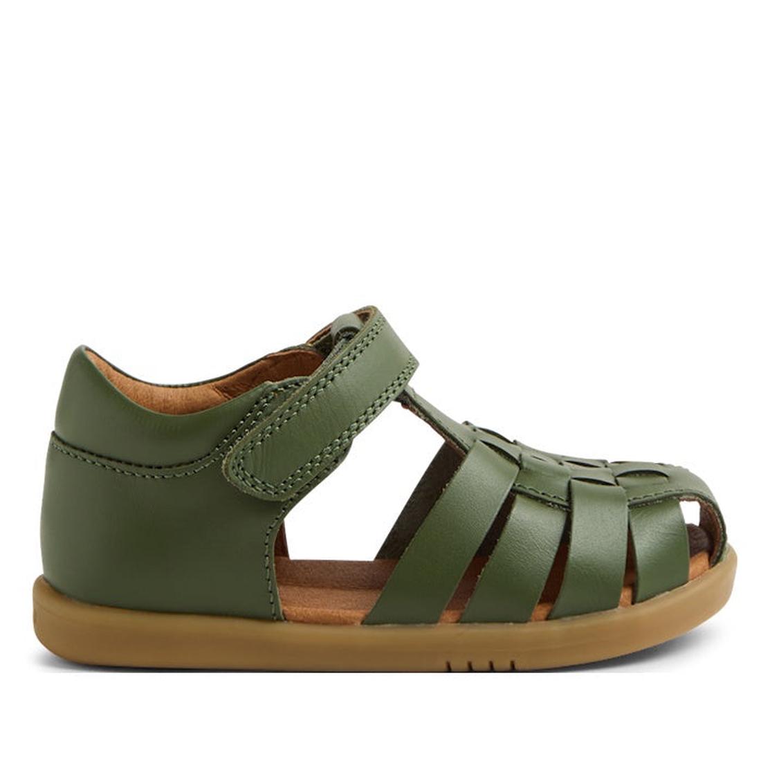 The Bobux IWalk Harbor Bronze Green Sandal is a children’s sandal with a light brown flexible sole, closed toe and heel, Velcro strap, water-friendly leather, and woven front design, shown side view on a white background.