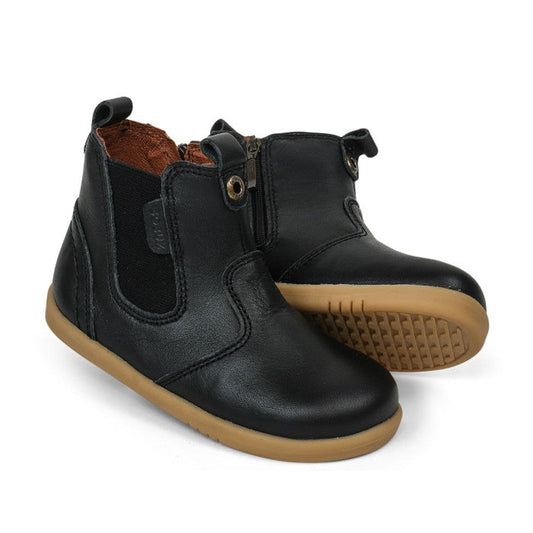 The Bobux Iwalk Jodhpur Outback Boot Black 620828A is a unisex children's boot in black leather with brown rubber soles, side zippers, pull tabs, and elastic panels—ideal for first-walkers and shown on a white background.