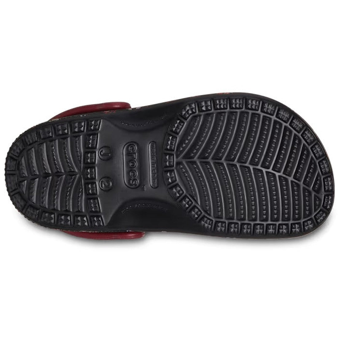 The image shows the sole of the Crocs Kids - Youths Classic Clog K Ditsy Floral Black Multi Sandal, featuring textured tread with horizontal, zigzag, and circular patterns for grip and the Crocs logo in the center, highlighting comfort., 196265775637, 196