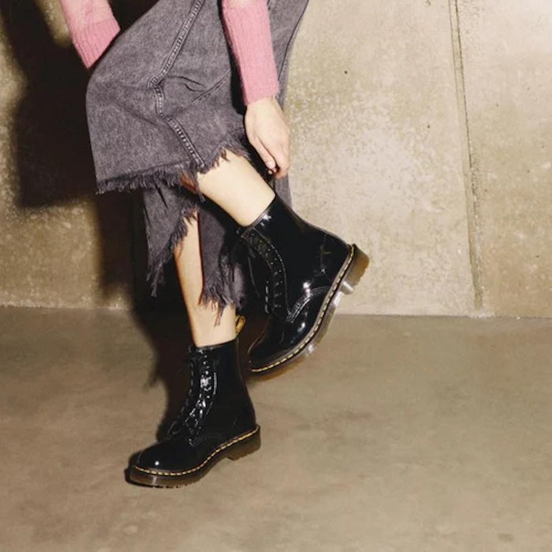 Person wearing DR Martens 1460 black patent leather boots with a textured beige background.,
883985035249,
883985035256,
883985035270,, 45130, 45131, 883985035249, 883985035256, 883985035270, 45138, 45139
