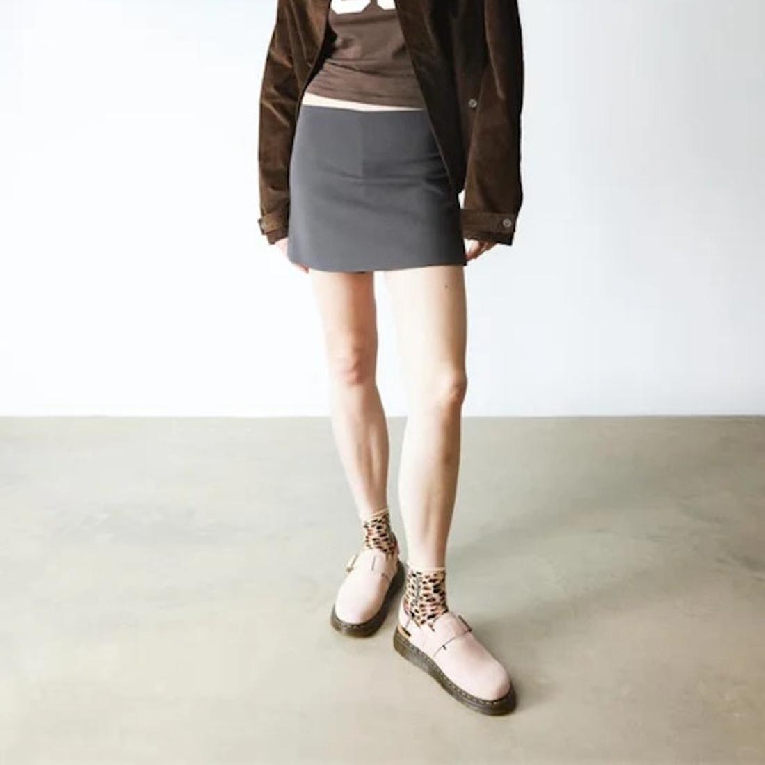 Person wearing a brown jacket, gray skirt, and Dr Martens Jorge pink Scuff mules with leopard print socjks on a plain background.,
190665705478,
190665705485,
190665705492,
190665705515,
190665705522,, 45123, 190665705478, 190665705485, 190665705492, 1906