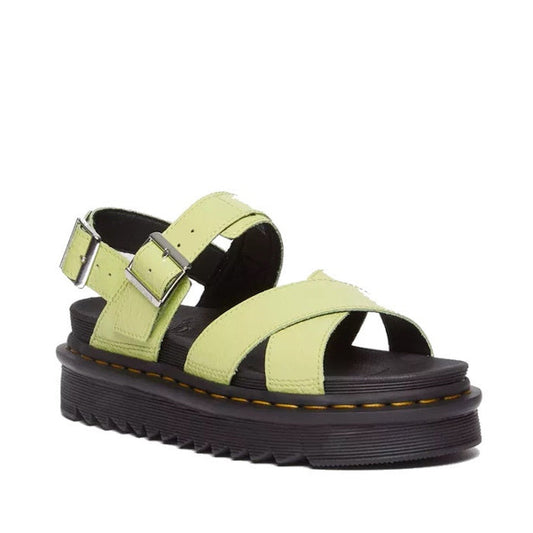 The Dr Martens Voss II Cross Strap Sandal features distressed patent lime green leather straps, adjustable silver buckles, and a thick black sole with signature yellow stitching.