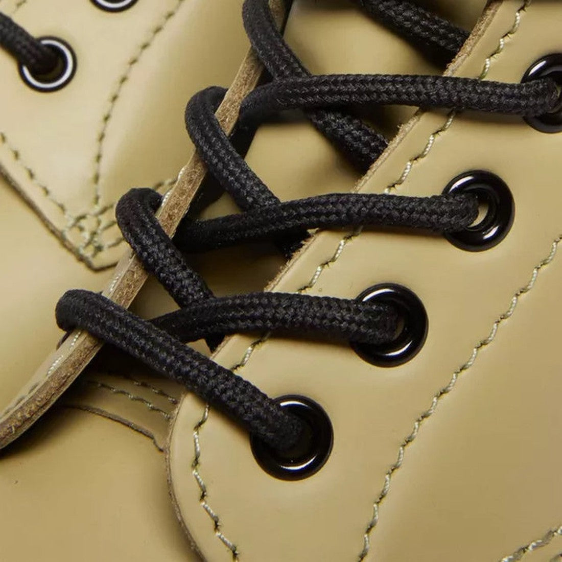 Close-up of black shoelaces threaded through black metal eyelets on pale olive smooth leather Dr. Martens 1460 8-eye boots, highlighting the stitching and material details., 190665531824, 190665531831, 190665531848, 190665531855, 190665531862, 19066553187