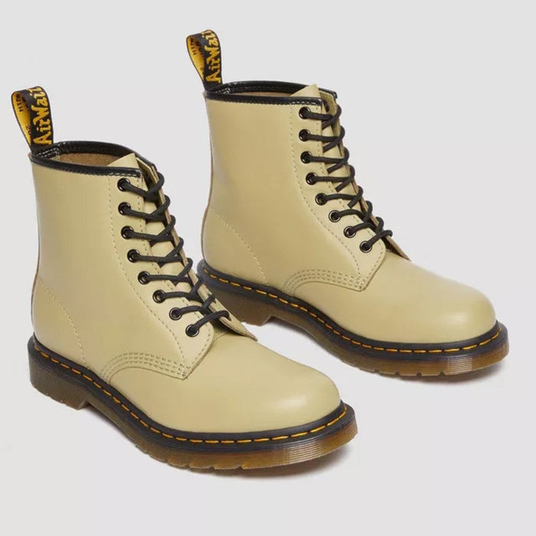 A pair of Dr Martens 1460 Smooth Pale Olive 8-Up Leather Boots with black soles, yellow stitching, and branded pull tabs at the back, crafted from smooth leather and shown on a light background., 190665531824, 190665531831, 190665531848, 190665531855, 190
