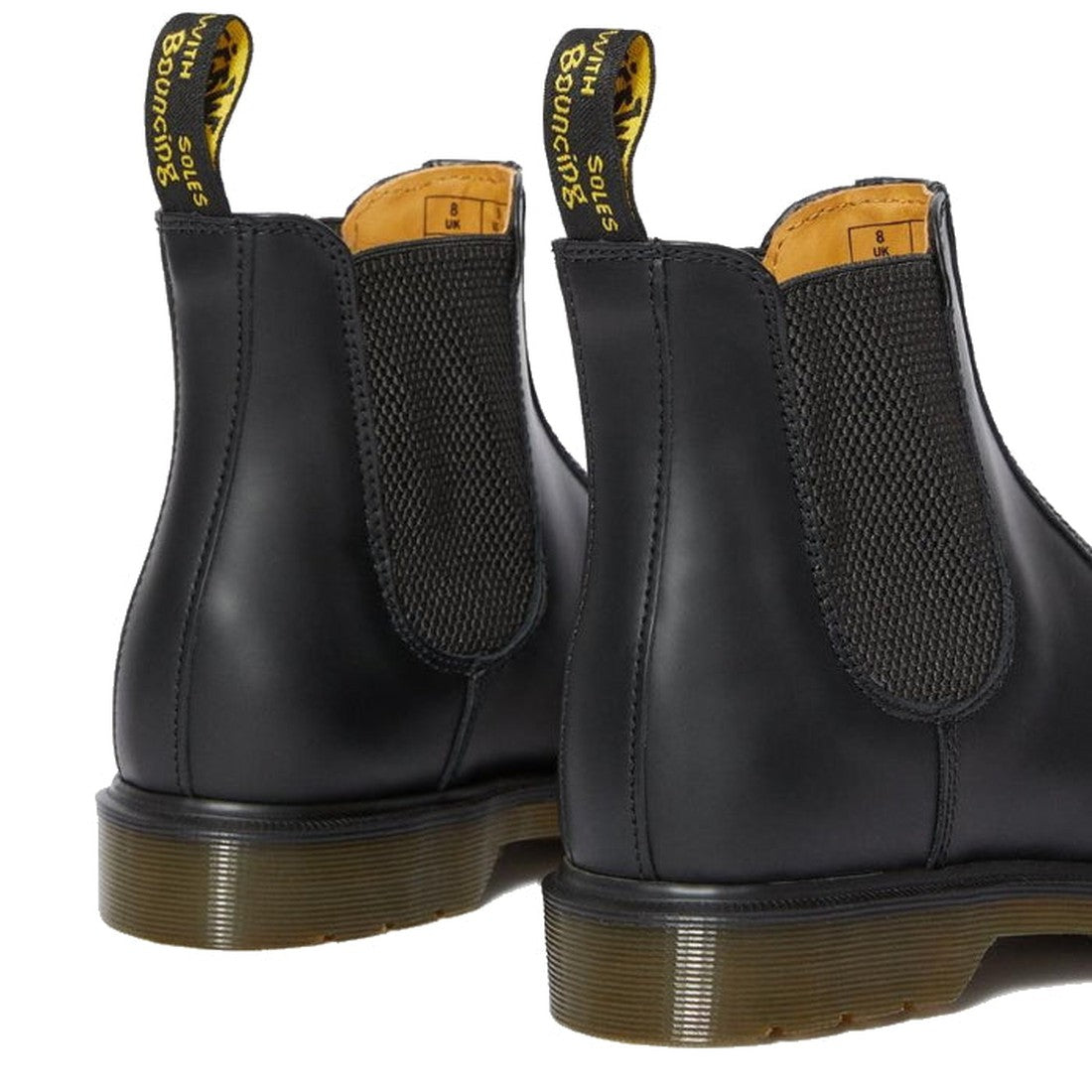 A close-up showing the back and side of Dr Martens -2976 Chelsea Boot Smooth Leather Black, featuring elastic panels, yellow stitching, and WITH SOLES BOUNCING yellow pull tabs., 800090824100, 800090800517, 22133, 800090824117, 800090824124, 800090824131,