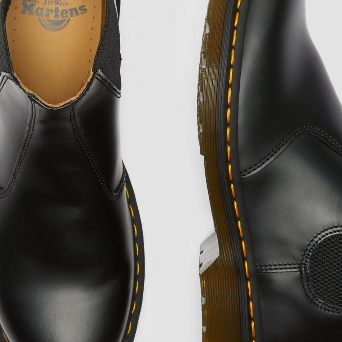 Close-up of two black Dr Martens 2976 YS Chelsea Boot Smooth Leather shoes featuring yellow stitching, elastic side panels, and visible sole—showcasing classic Chelsea boot details from a top and side angle., 883985986695, 883985986701, 883985986718, 8839