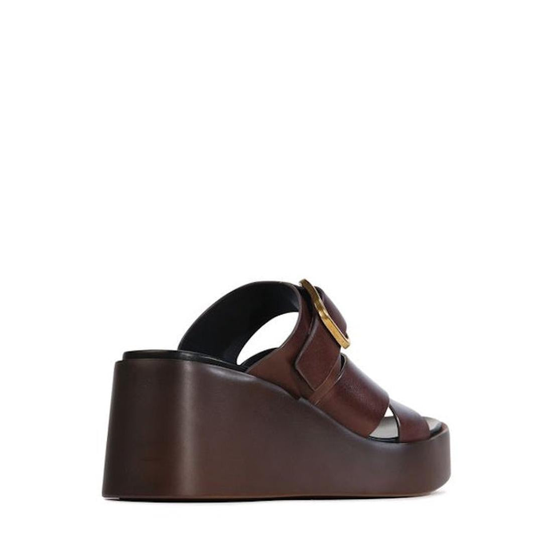 The EOS Aris Womens Chestnut Brown Leather Wedge Slide features an anatomical footbed, open toe, wide leather straps, and a large circular side buckle, shown in profile against a white background., 48005, 9321191293646, 9321191293653, 9321191293660, 93211