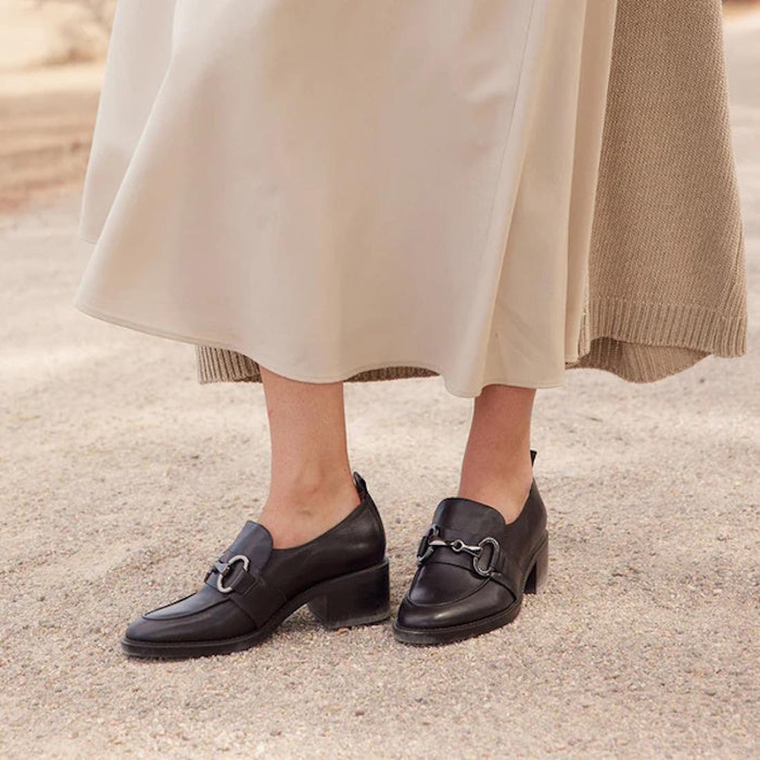 A parent steps out on a sandy path in EOS Keily Black Leather Heeled Loafers, comfy slip-ons with block heels and chain accents.  ksnz, 9321191193403, 9321191193410, 9321191193427, 9321191193434