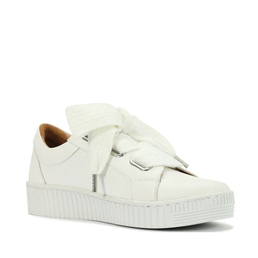 The EOS Jovi Leather Trainer is a stylish white lace-up sneaker crafted from Italian Aniline leather, featuring a thick sole, metallic accents, oversized textured ribbon laces tied in a bow, a smooth finish, low-cut design, and convenient side zip.