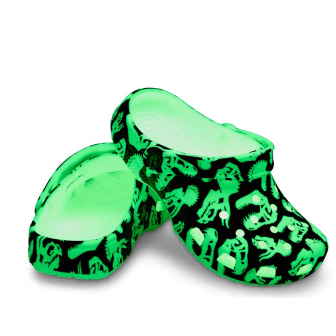The Crocs Kids - Youths Classic Glow Dino Clog K Black Sandal features a black base with glowing green dinosaur skeleton patterns, showcasing a playful glow-in-the-dark design perfect for kids., 198445261459, 198445261466, 198445261473, 198445261480, 1984