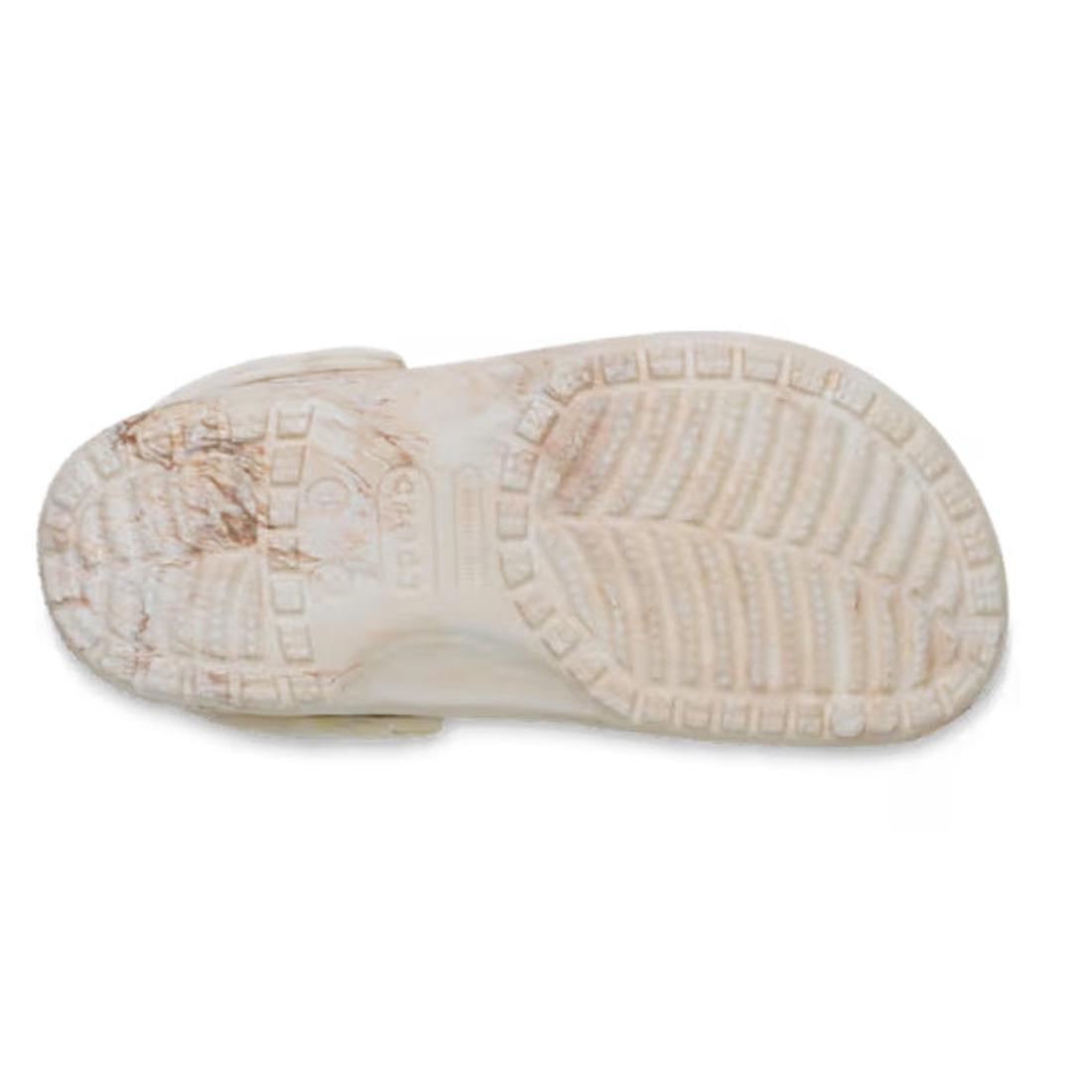 The sole of a Crocs Kids Watercoloured Marbled Clog Sandal Bone Swirl Youths is shown from the bottom, highlighting its tread pattern, texture, and visible brown dirt stains on the Croslite foam material., 198445279461, 198445279478, 198445279485, 1984452
