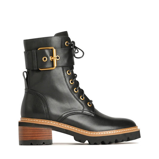 The EOS Line Black Women's Leather Boot features gold eyelets, a decorative ankle strap, buckle detail, chunky stacked heel with wood-like finish, thick tread sole, and a lace-up front for a stylish combat look.