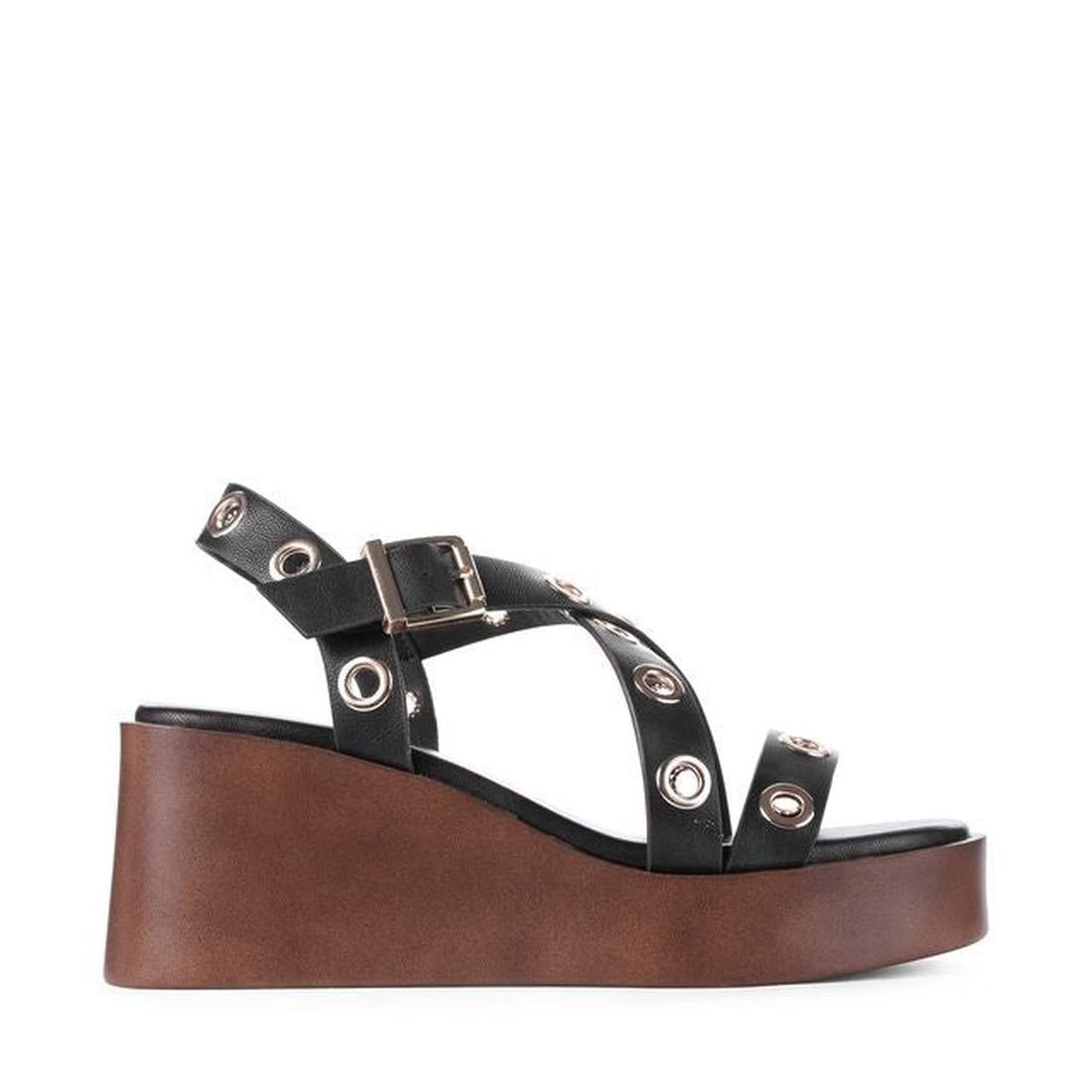 The Los Cabos Lagos Black Women's Wedge Heel Sandal features black straps with silver grommets, a buckle, and a thick brown wedge heel platform, displayed in side profile on a white background., 9321191309392, 9321191309408, 9321191309415, 9321191309422, 