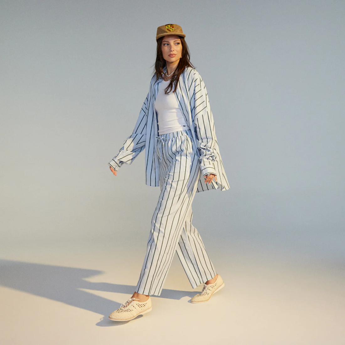 A cheerful woman walks in Rollie Women's Derby Open Weave Oat Off White Trainers: comfy lace-ups, airy design, soft sole—perfect for busy days.  ksnz, 9781760774608, 9781760774615, 9781760774622, 9781760774639, 9781760774646