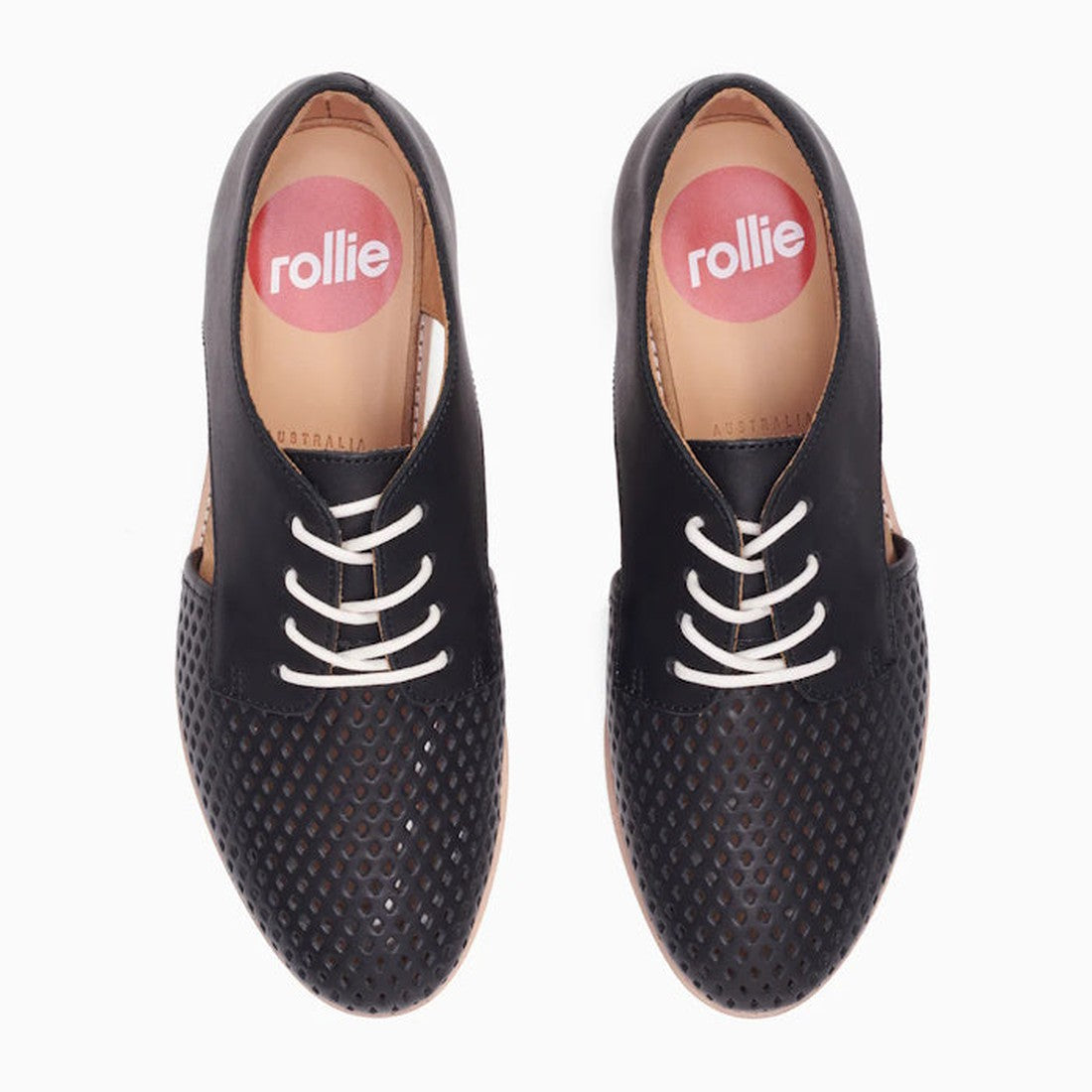 The Rollie Womens Sidecut Punch Black Leather Shoe features black perforated leather, white laces, cushy EVA midsoles, and insoles marked with a pink circle and "rollie" in white—breathable and comfy, viewed from above., 9339554249179, 9339554249186, 9339