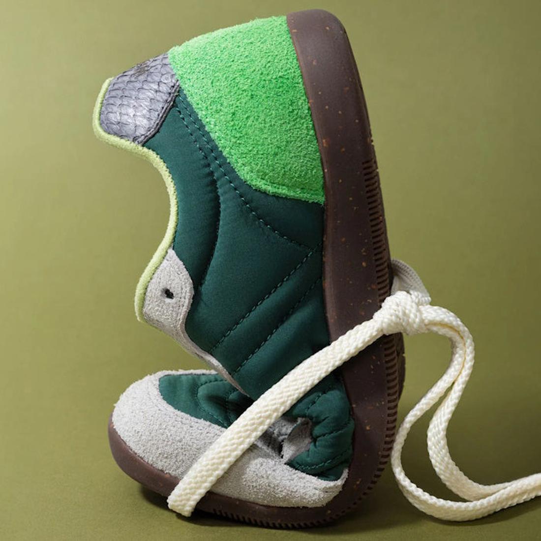 The Woden Nanna Apple Green Multi Lace Up Sneaker, featuring a brown sole and white laces, is flexed heel to toe against an olive-green background, showcasing its packable, travel-friendly design., 50250, 5713326697834, 5713326697841, 5713326697858, 50253