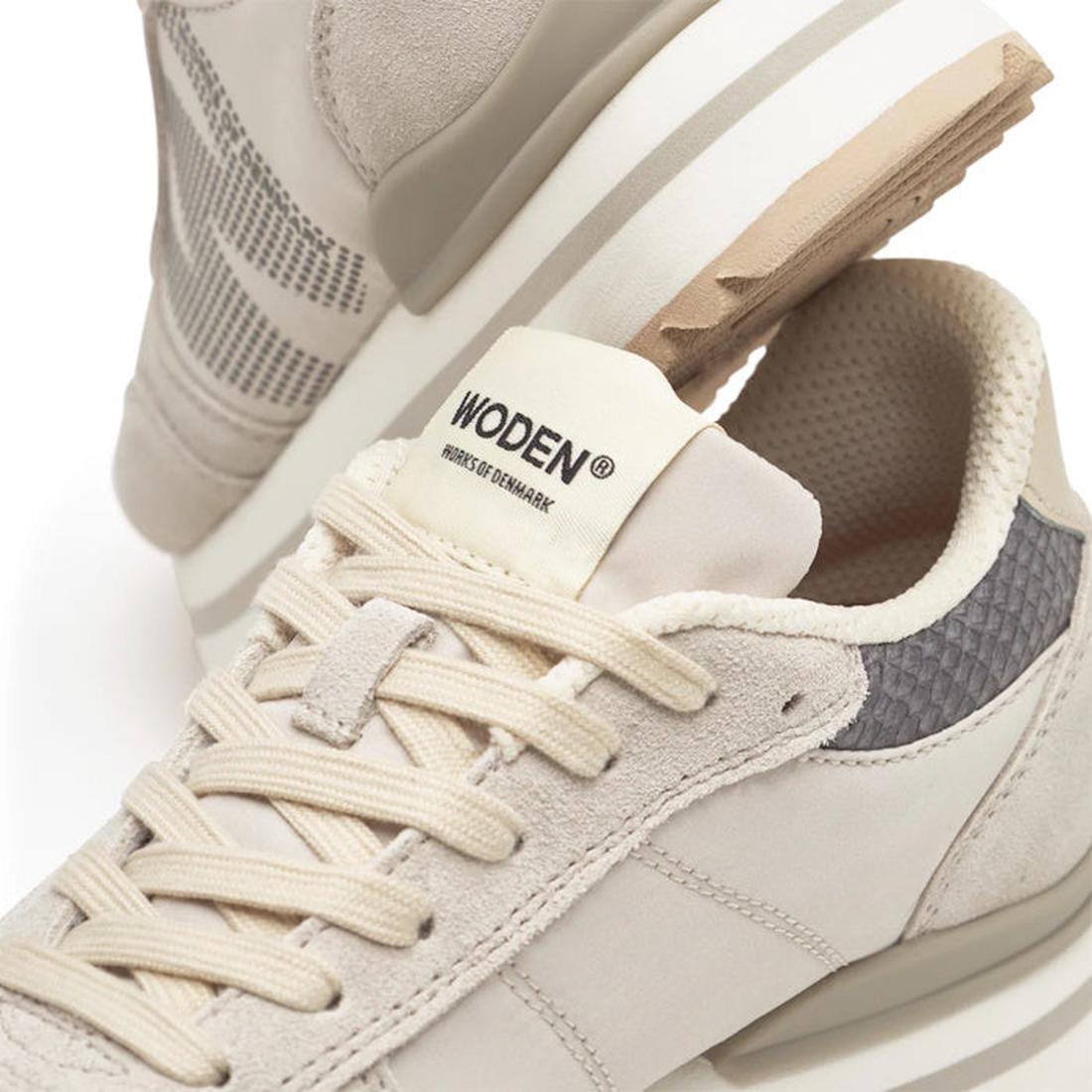 A close-up of Woden Ronja Plateau Delpin Lace Up Sneakers in beige and gray, highlighting laces, side panels, fish leather heel accents, and a “WODEN - HOUSE OF DENMARK” brand label on the tongue., 5713326692365, 5713326692372, 5713326692389, 571332669239