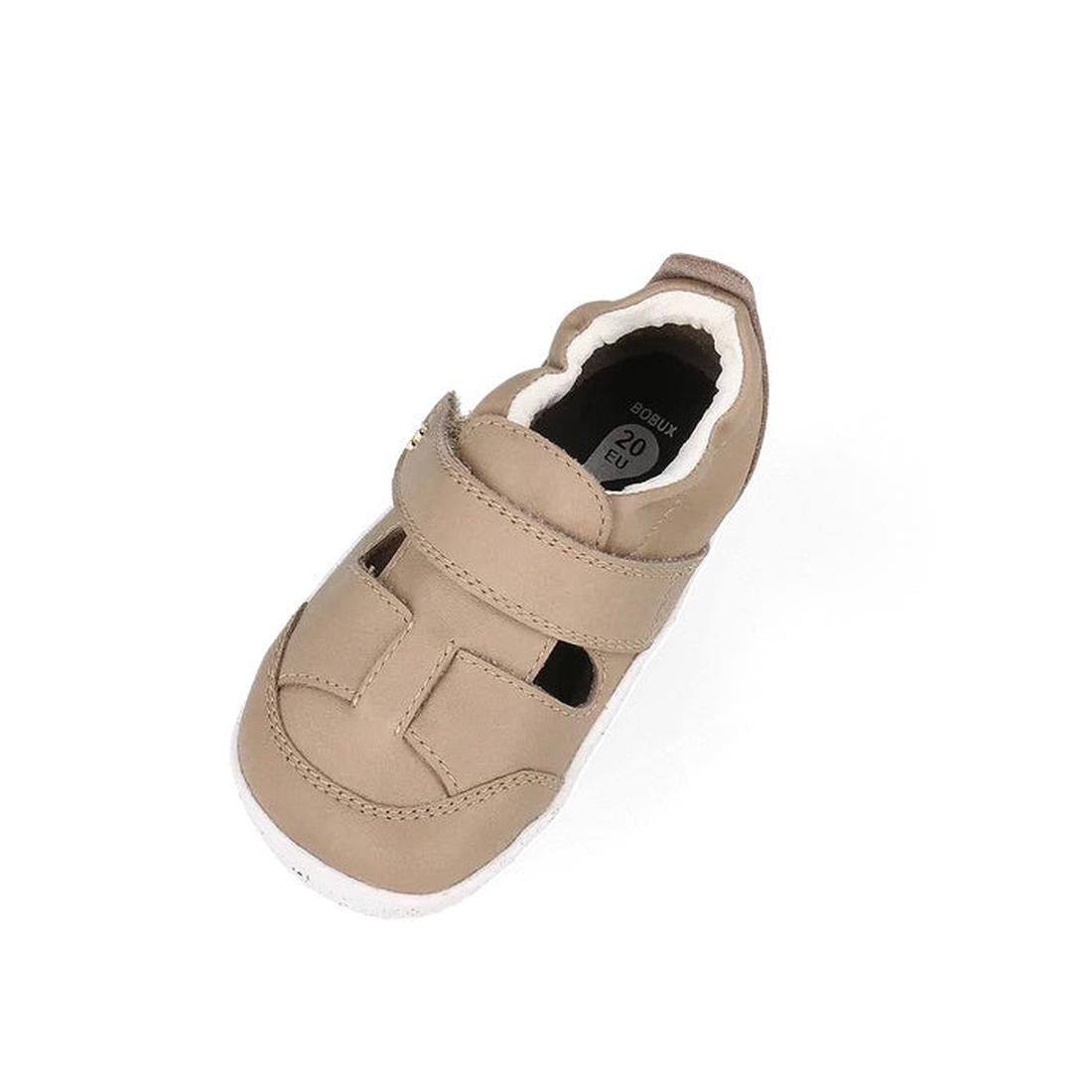 The Bobux XP Explorer Beau First Walker Sandal Atmosphere 502301 is a beige closed-toe learning-to-walk shoe with a white flexible sole and velcro strap, shown against a plain white background., 9420075784338, 9420075783690, 9420075786172, 9420075784239