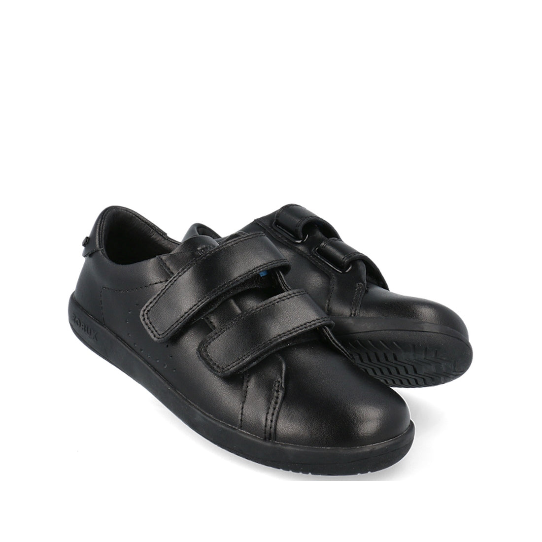 The Bobux Kid+ Bound Black Leather School Sneaker Shoe is displayed against a white background, with one shoe upright and the other on its side to show the textured sole and dual adjustable straps.
