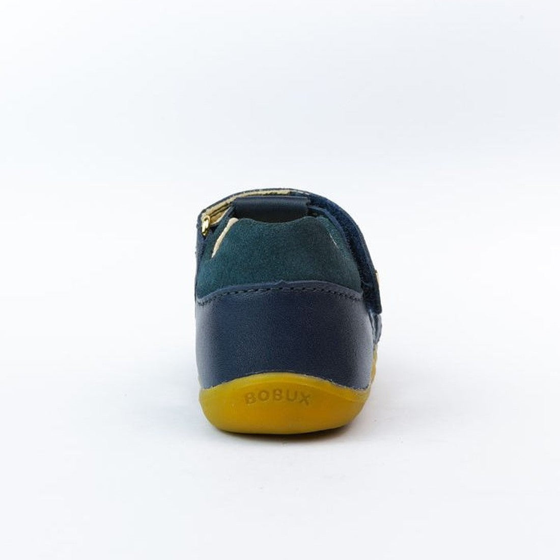 A single small Bobux Step Ups Cross Jump Navy Closed Toe Sandal is shown from the back, featuring dark blue leather and green suede upper, a yellow rubber sole, and "BOBUX" embossed on the heel. The background is plain white., 9420062083567, 9420062083574