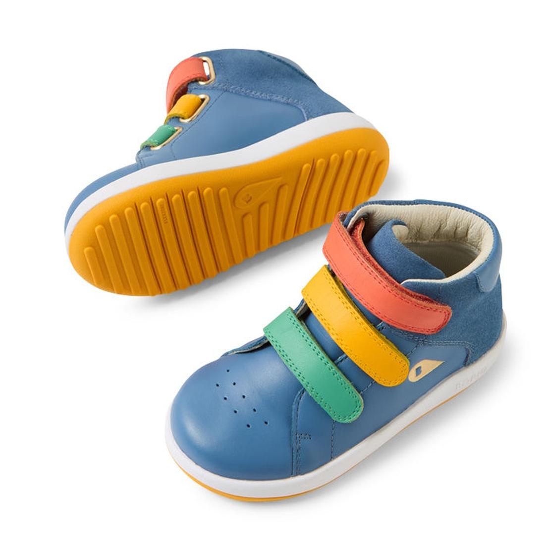 The Bobux IW Iwalk Gamepoint Leather Boot in Coronet Blue is a children's sneaker featuring yellow soles and velcro straps in red, yellow, and green. One shoe stands upright while the other is tilted to display its anti-slip rubber outsole., 9420074815170