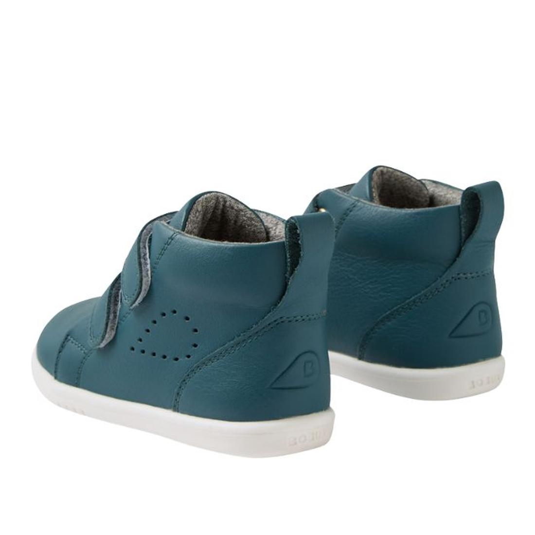 The Bobux IW Iwalk Grass Court Hi Leather Boot in Mediterranean Green features white soles, side perforations, and adjustable Velcro straps. The kids’ shoes are shown facing away and slightly to the side on a white background., 9420074856814, 942007485682
