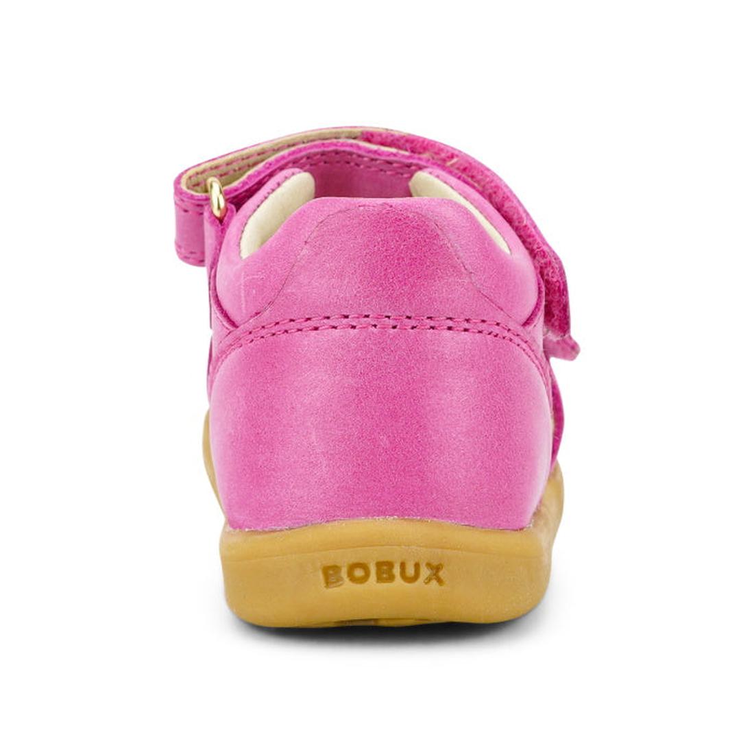 A close-up rear view of the Bobux iwalk IW Magic Girls Leather Sparkle Sandal in bright pink, featuring a tan rubber sole with stitching, a strap, and embossed BOBUX branding—ideal first-walker shoes., 9420068522749, 9420068522756, 9420068522763, 94200685