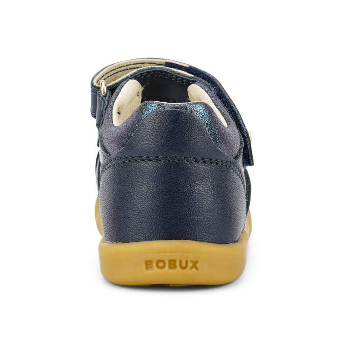 A rear view of the Bobux iwalk IW Magic Girls Leather Sandal in navy blue leather with a light brown sole and BOBUX branding on the heel. This girls' sandal features a strap, open toe design, and padded ankle for comfort., 9420068522572, 9420068522589, 94