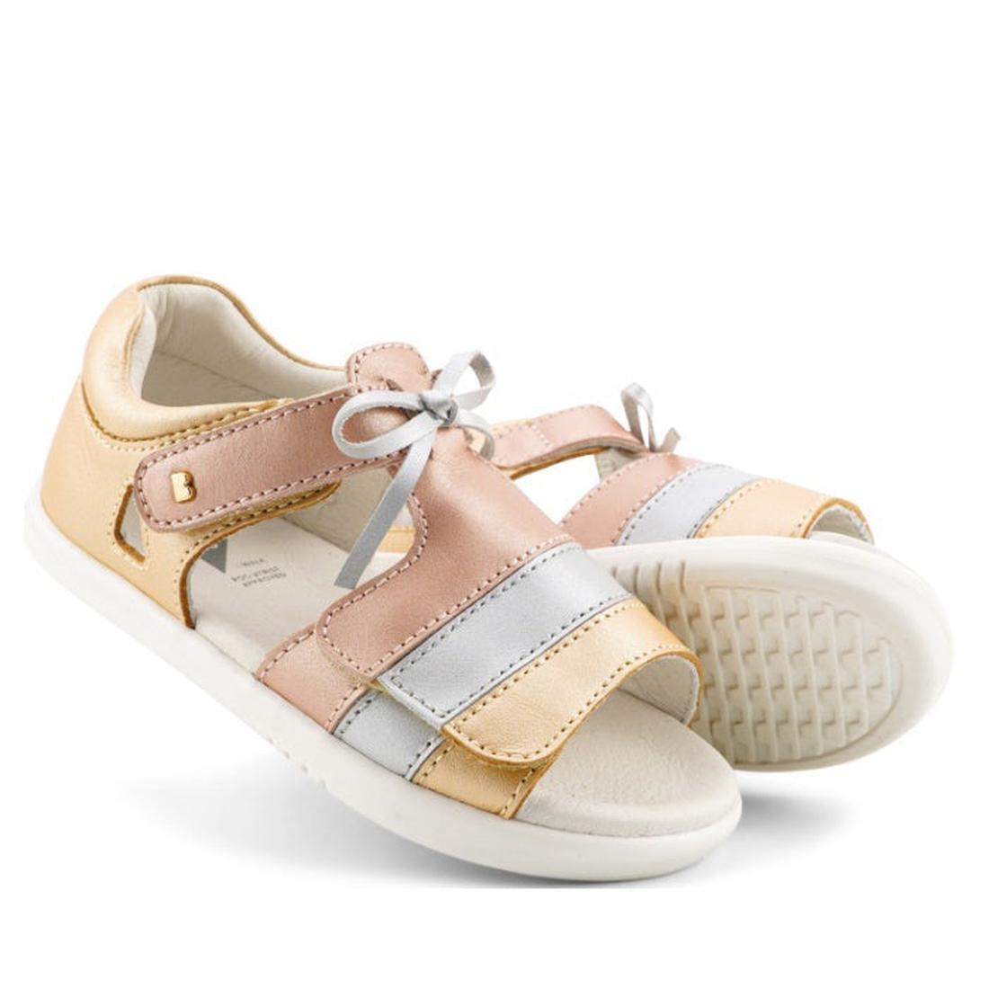 Bobux IW Iwalk Mirror Pale Gold 633433 are girls' open-toe sandals in metallic gold with white soles, a silver bow, strap closures, and soft cushioned insoles. Premium leather construction.
