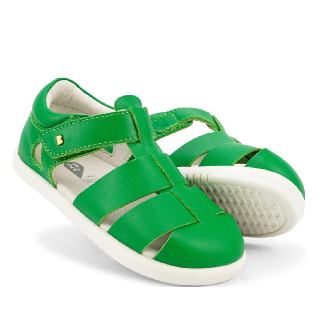 A pair of Bobux Iwalk IW Quick Dry Tidal Sandal 634402 in Emerald Green with white soles and closed toes. One stands upright, the other lies on its side to display the textured sole. Both have velcro straps for fastening.
