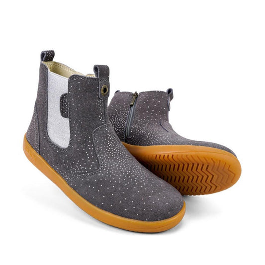 The Bobux Iwalk Jodphur Boot Charcoal Starburst 620857 features gray suede leather with white speckles, white elastic side panels, side zippers, pull tabs, and light brown rubber soles. One boot is upright; the other lies on its side.