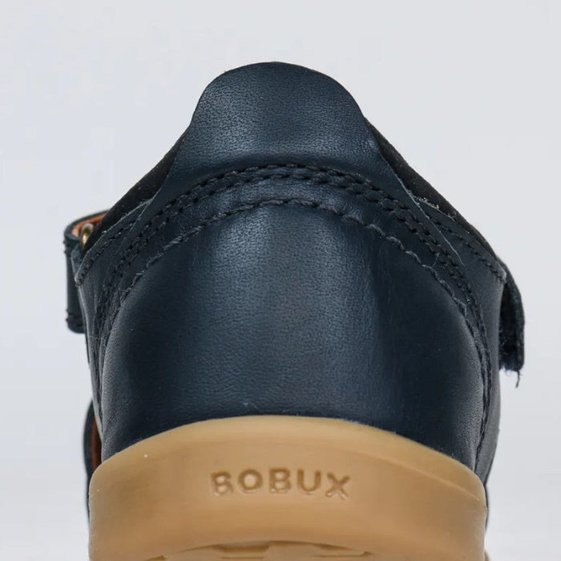 Close-up of the back of the Bobux Kid+ Plus Roam Navy Closed Toe Sandal 830503A with visible stitching, tan rubber sole, and BOBUX embossed on the heel—an ideal choice for boys' closed toe sandals., 9420062049884, 9420062049891, 9420062049907, 94200620499