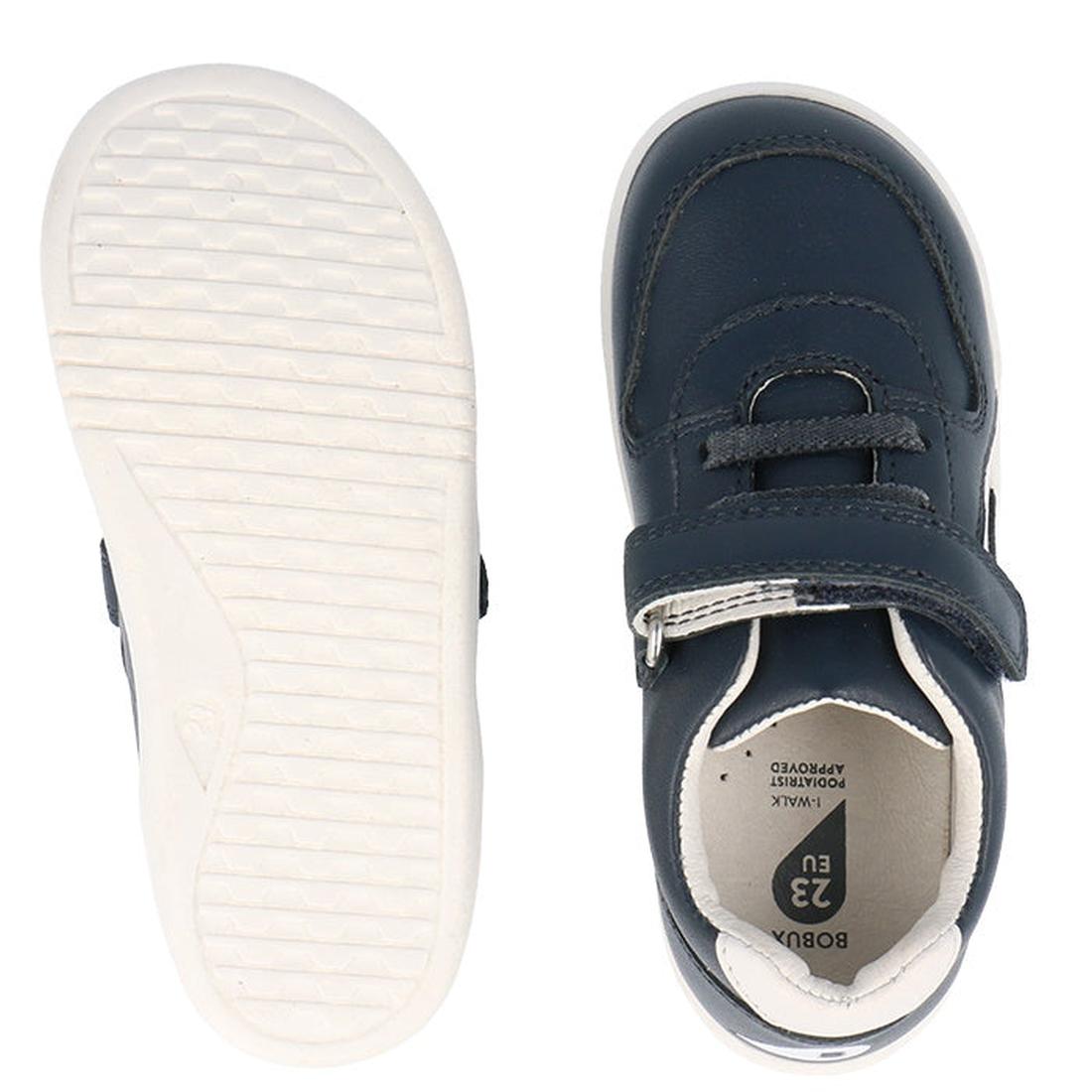 A pair of Bobux Kids IWalk IW Comet Sneakers in Navy/White for toddlers is shown: one retro unisex leather shoe with a Velcro strap from above, the other flipped to reveal its textured white sole., 9420075706118, 9420075706125, 9420075706132, 942007570614