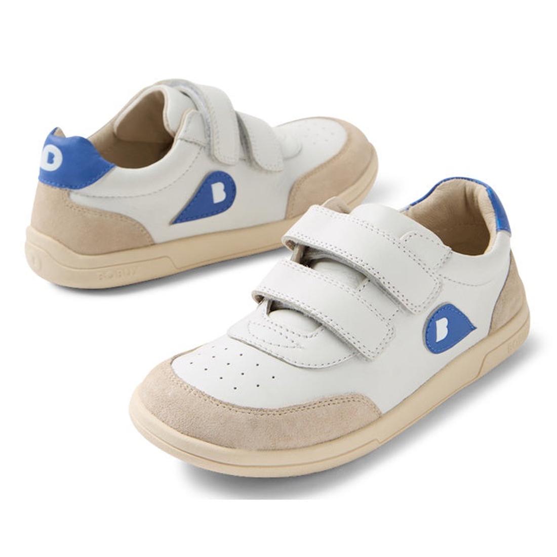 The Bobux KP Kids Plus Champ II Sneaker White Blue Juniors is a white and beige kids' leather sneaker with blue accents, two Velcro straps, a durable sole, and a blue patch with a white "B" on the side.