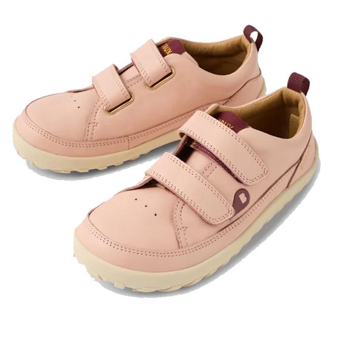 The Bobux Kid+ Dawn Leather Sneaker Cameo Rose Pink Alpha features a barefoot-shaped toe box, beige soles, two velcro straps, and maroon accents on the heel tab and tongue in light pink leather for kids.