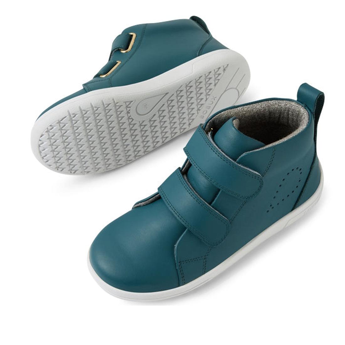 The Bobux KP Grass Court High II Boot Mediterranean Green Juniors are kids’ teal leather high-top sneakers with white rubber soles, two adjustable straps, and a back loop for easy pull-on. One shoe is upright, the other shows the sole pattern., 9420074859